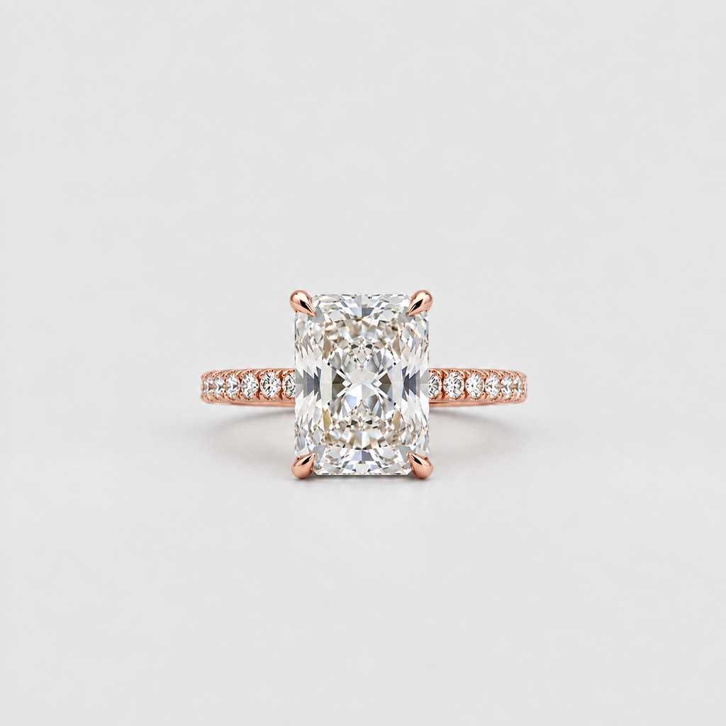 A rose gold engagement ring featuring a large rectangular radiant-cut diamond center stone and a pavé band set with small round diamonds, shown on a clean light gray background.