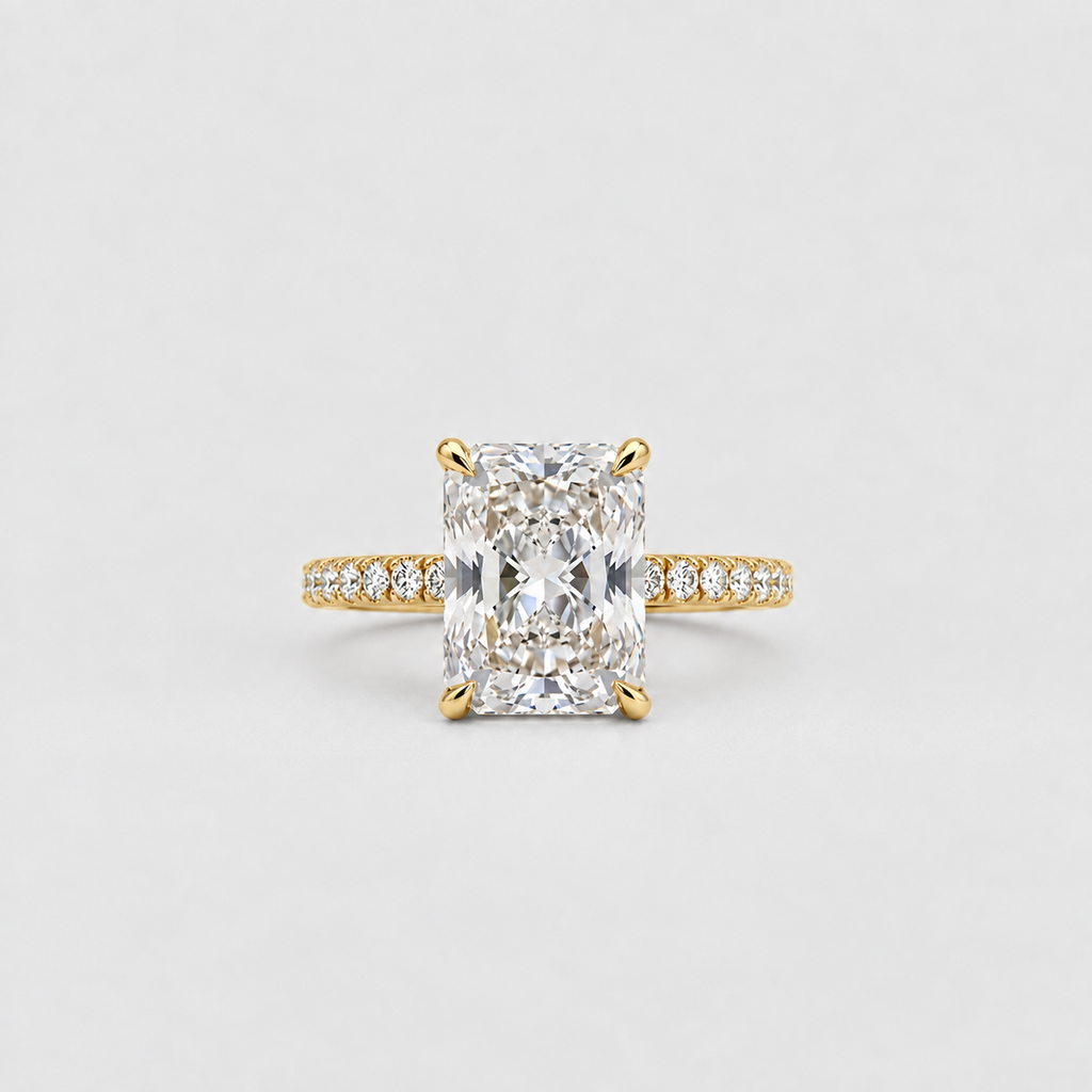 A yellow gold engagement ring featuring a large rectangular radiant-cut diamond center stone and a pavé-set diamond band, centered on a light gray background.