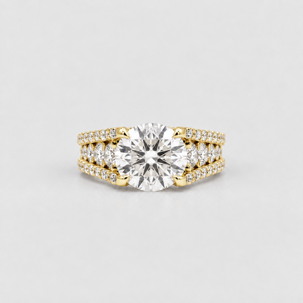 A yellow gold engagement ring set featuring a large round-cut center stone with smaller pavé-set diamonds along the shoulders, photographed on a clean light gray background.