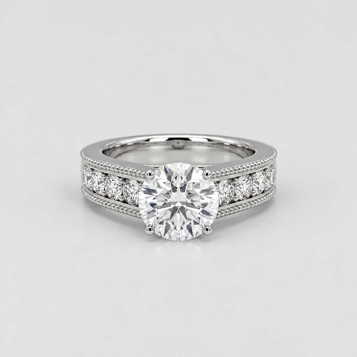 A silver-toned diamond ring with a large round-cut center stone and smaller diamonds set along the shoulders, shown on a light gray background.