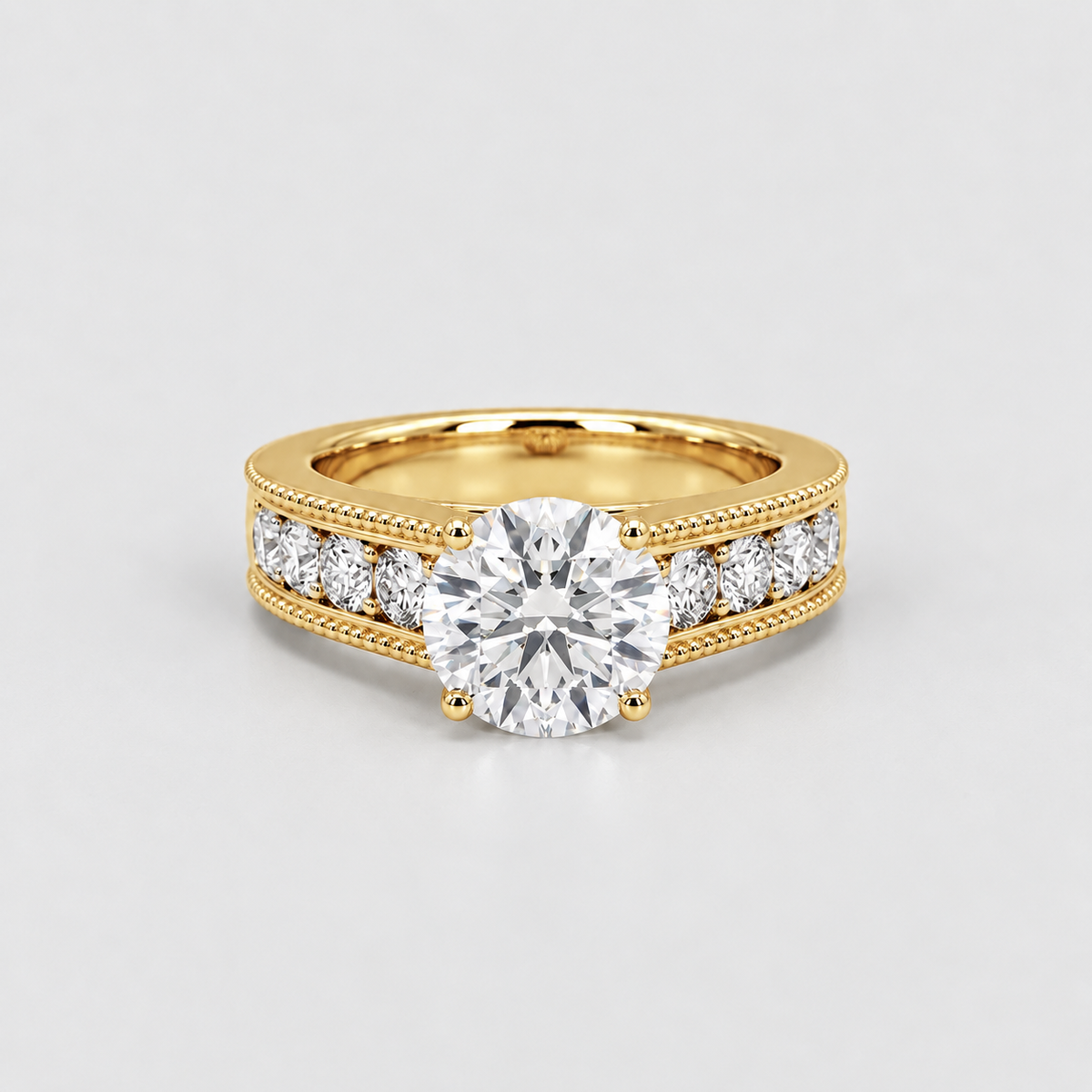 A yellow gold diamond ring with a large round center stone and smaller diamonds set along the shoulders, photographed on a clean light gray background.