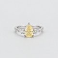 A pear-cut yellow diamond ring with a silver-colored band and small clear accent diamonds on either side, photographed on a clean light gray background.