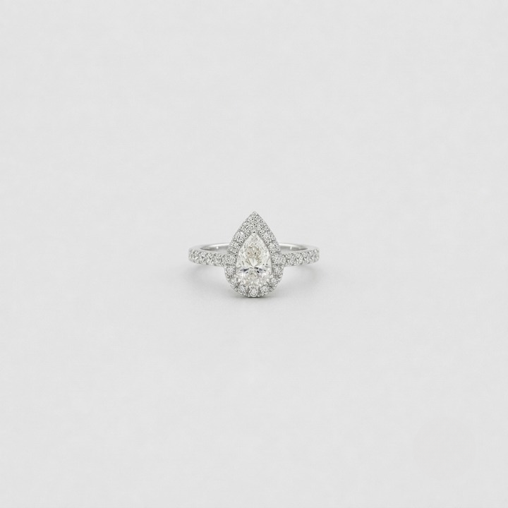 A pear-cut halo ring with a pavé band, set in a silver-toned metal on a light gray background.