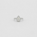 A pear-cut halo ring with a pavé band, set in a silver-toned metal on a light gray background.