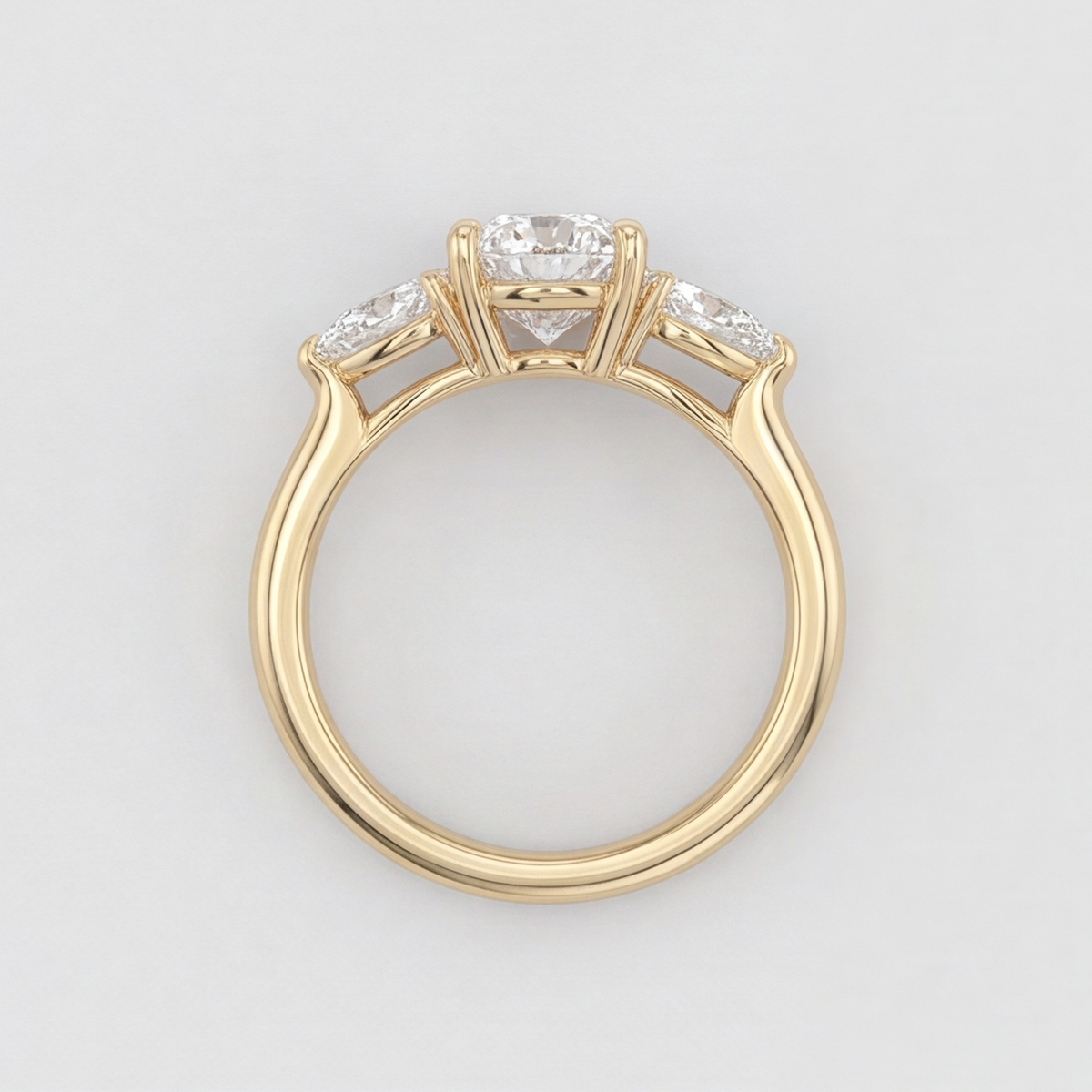 A yellow gold ring featuring a three-stone diamond solitaire setting with a round center diamond and marquise-cut side diamonds, shown on a light gray background.
