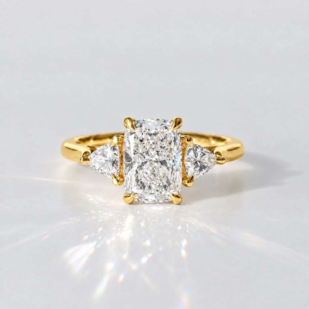 A yellow gold ring featuring a large rectangular radiant-cut diamond center stone with two smaller marquise-cut diamonds on either side, set against a clean white background with a soft reflection.