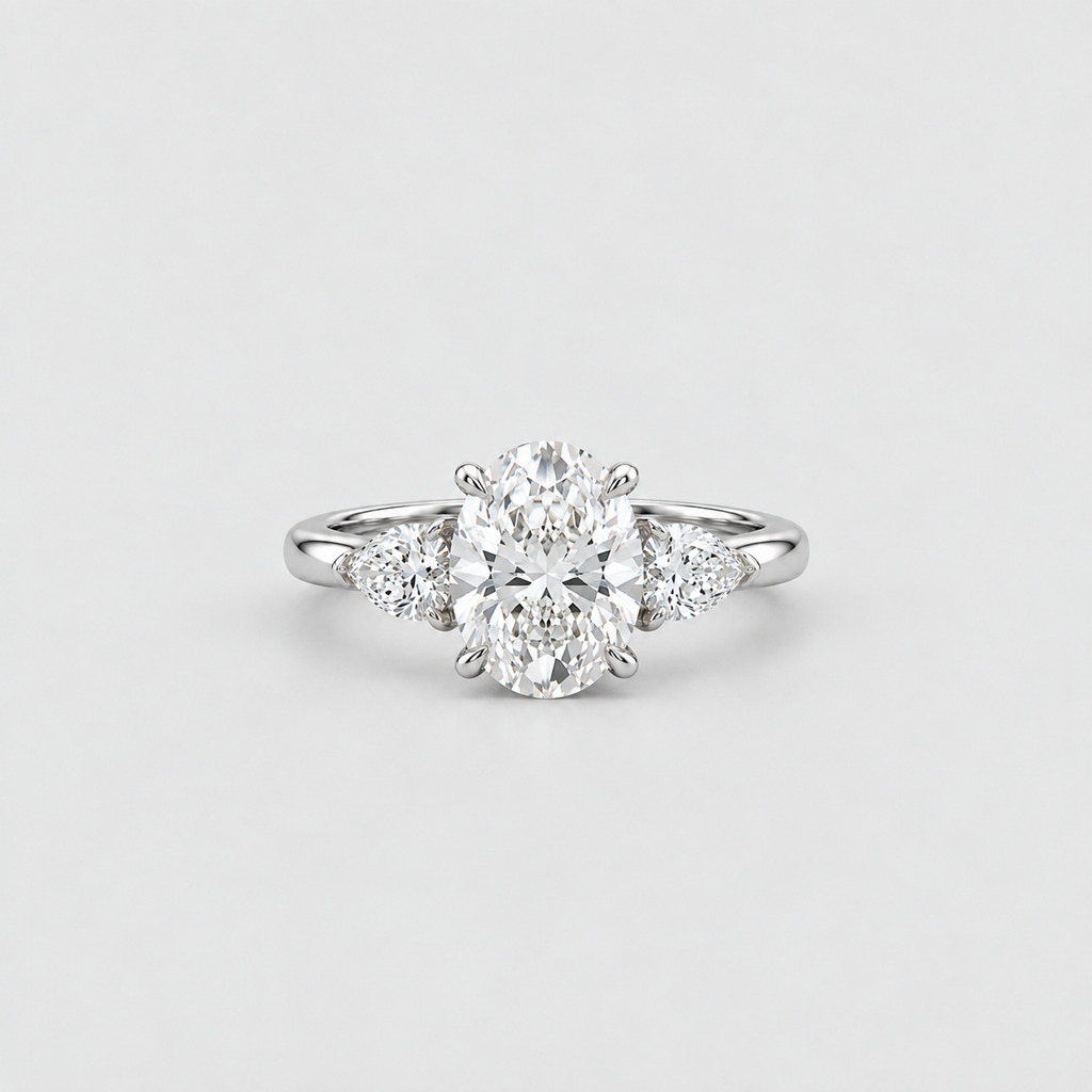 A silver diamond ring with a large oval center stone and three smaller round diamonds flanking it on a clean light gray background.