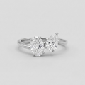 A silver-toned ring featuring two pear-cut diamonds in a split setting, photographed on a clean light gray background.
