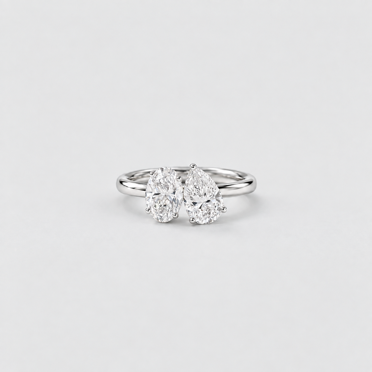 A silver double diamond ring with two pear-cut diamonds in a three-prong setting, shown on a light gray background.