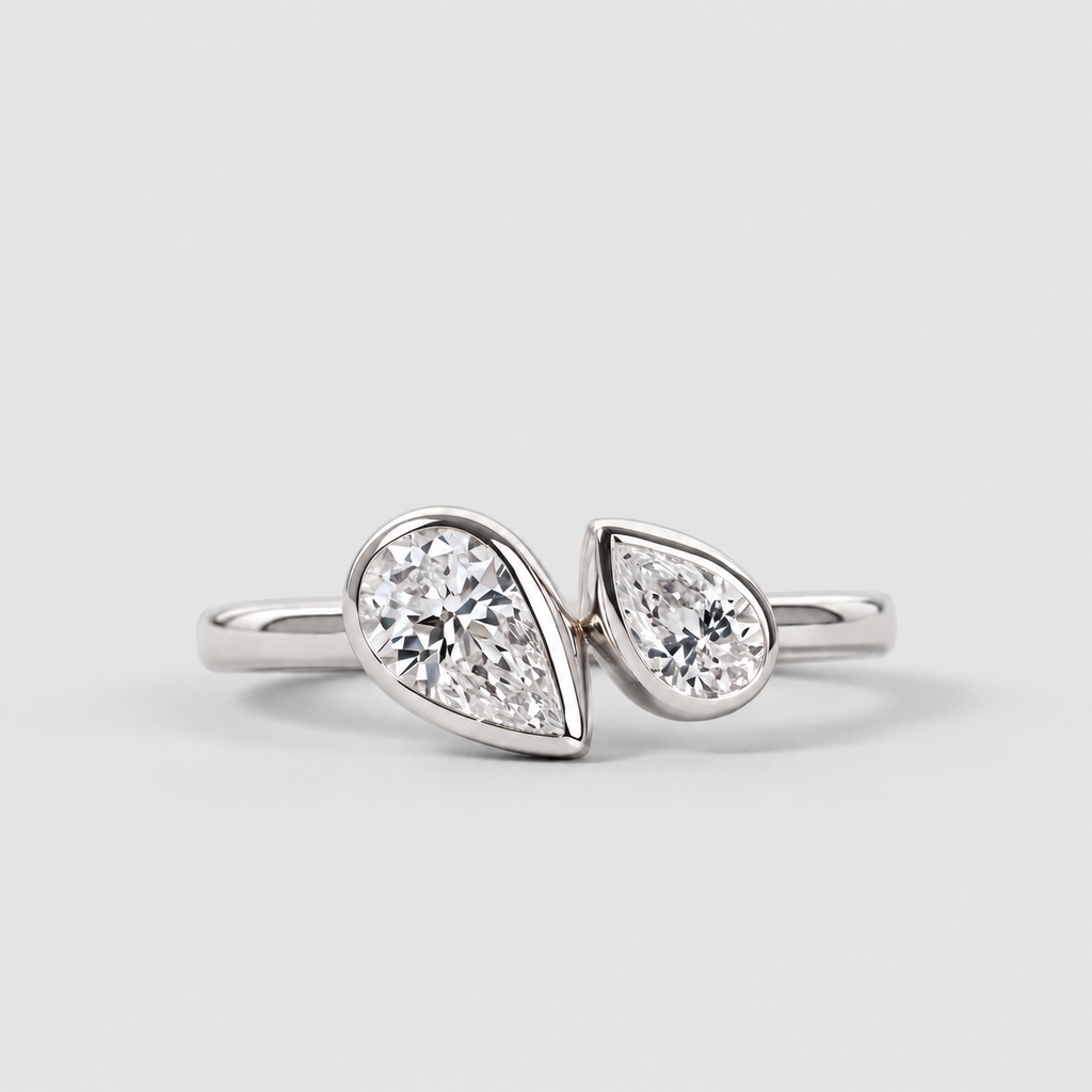 A silver ring featuring two pear-cut diamonds set in a split design, photographed on a clean light gray background.