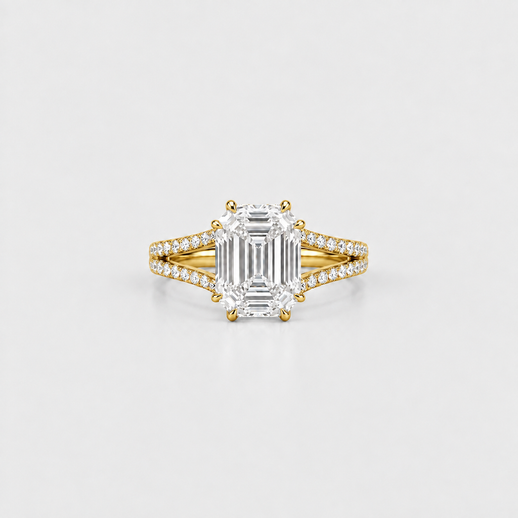 An emerald-cut diamond ring with a yellow gold band accented by pavé diamonds, centered on a light gray background.