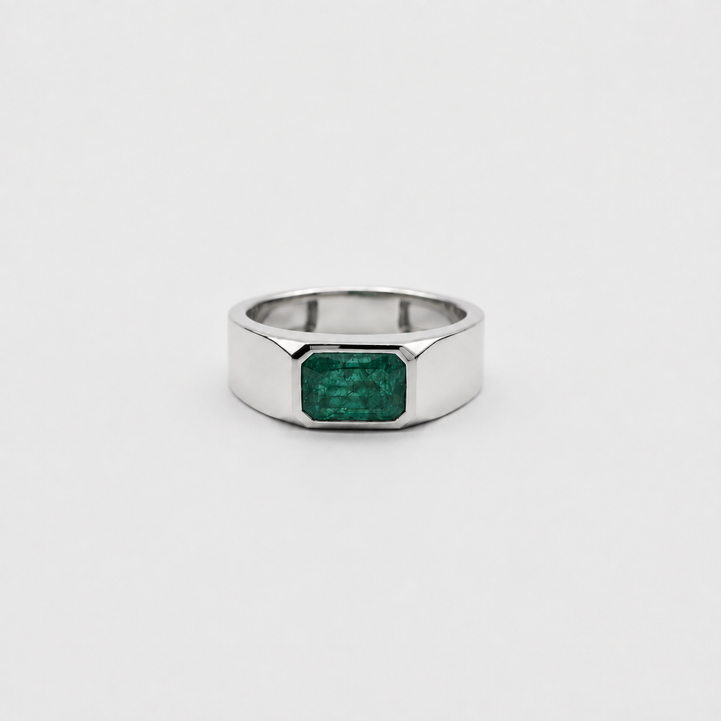 A silver-toned ring with a faceted octagonal band and a rectangular green emerald-cut gemstone, centered on a light gray background.