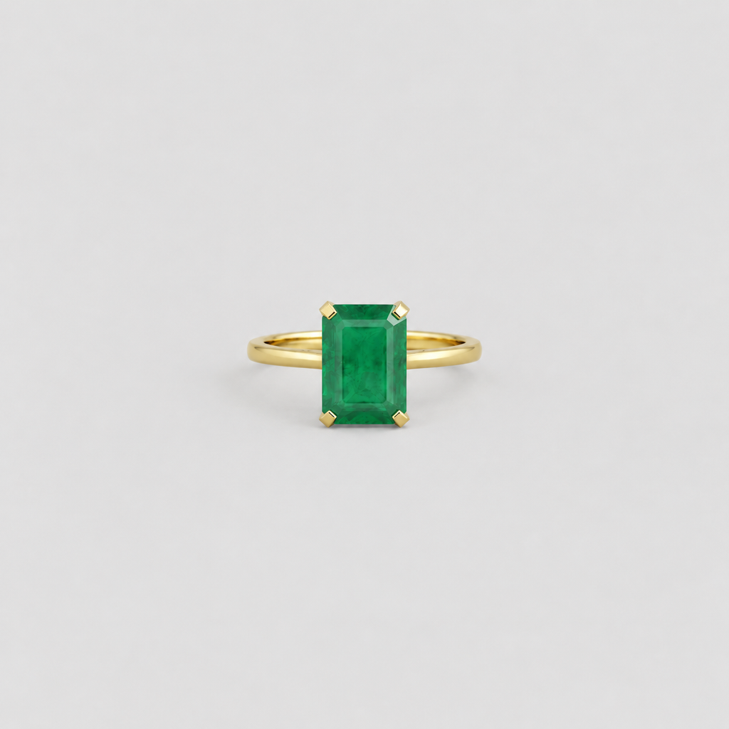 A yellow gold ring featuring a rectangular emerald-cut green gemstone in a four-prong setting, centered on a light gray background.