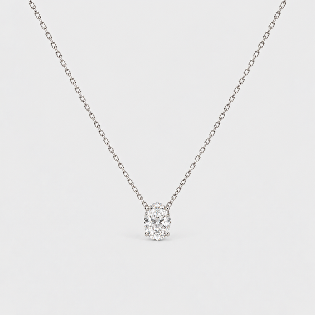 A delicate silver chain necklace with a small, clear round-cut gemstone pendant set in a prong setting, shown against a light gray background.