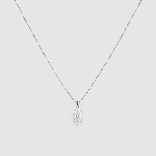 A delicate silver chain necklace with a small, clear, marquise-cut gemstone pendant, displayed against a solid light gray background.
