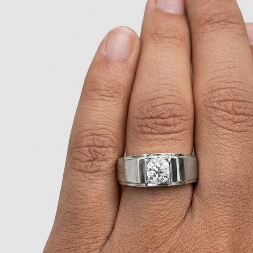 Silver ring with a diamond on a person's finger against a light gray background