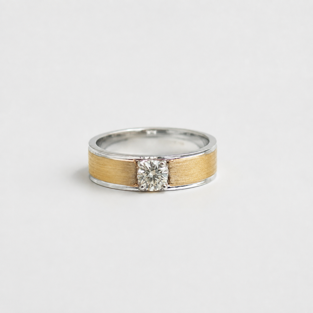 A two-tone ring with a brushed gold center band, silver-colored metal shoulders, and a round-cut clear gemstone, shown on a light gray background.