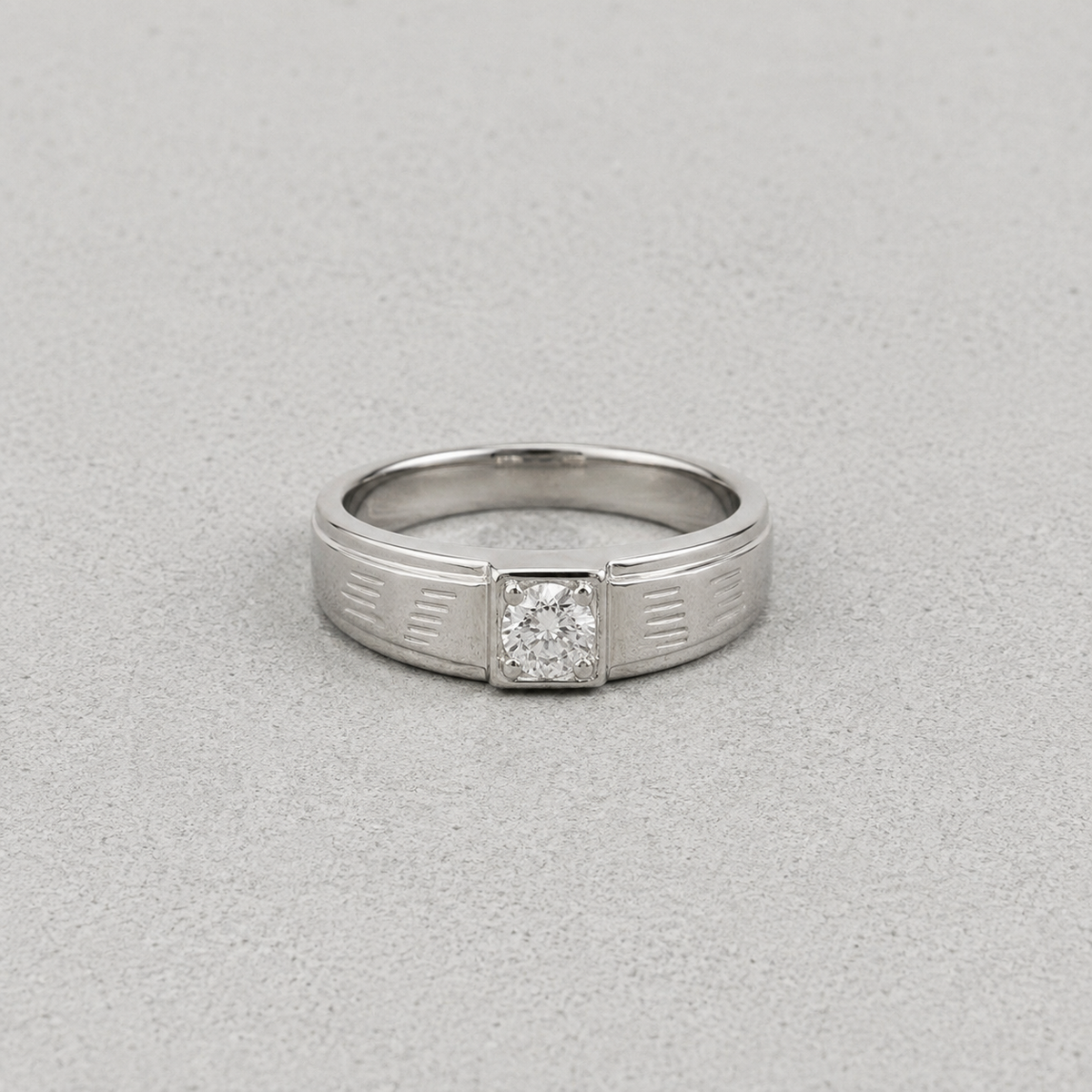 A silver ring with a square-cut diamond set in a decorative bezel, shown on a textured gray background.