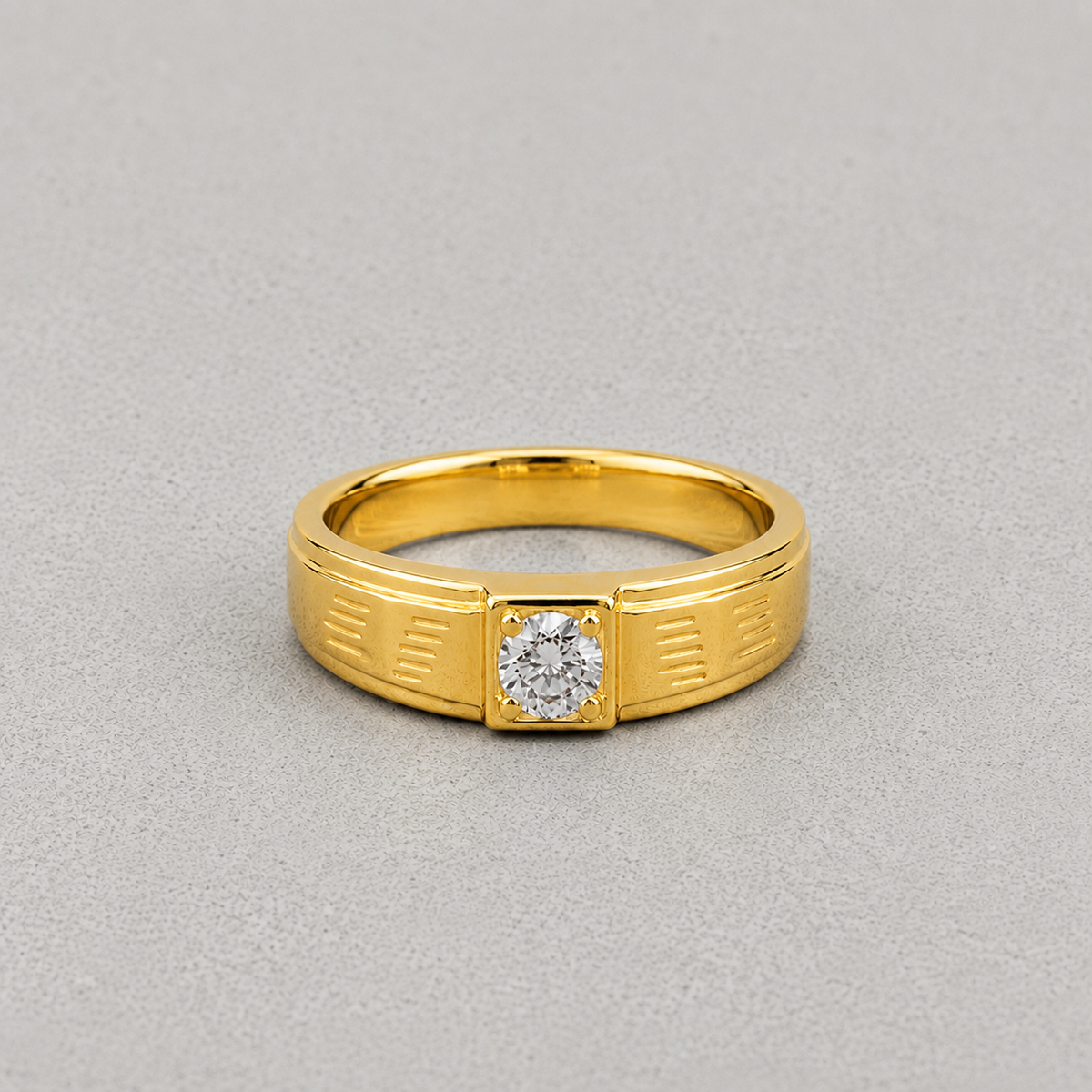 A yellow gold ring with a square bezel setting holding a round-cut clear gemstone, photographed on a neutral gray background.