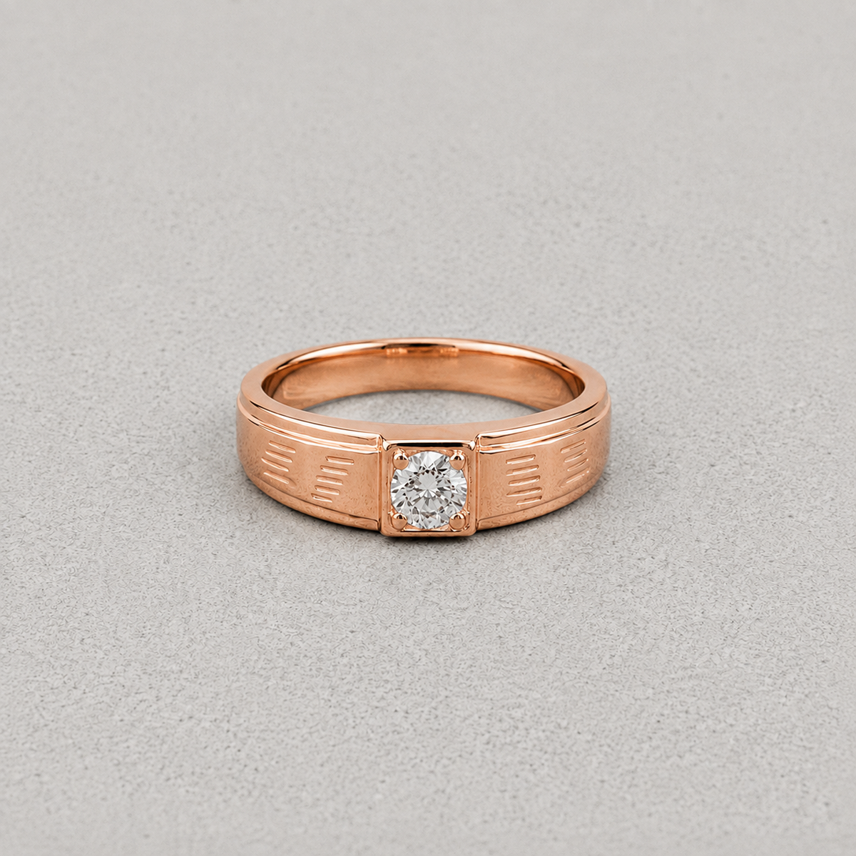 A rose gold ring with a square bezel holding a round-cut clear gemstone, set against a textured light gray background.