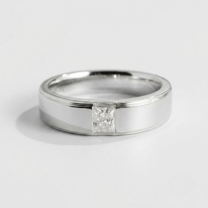 A polished silver band ring featuring a single princess-cut diamond solitaire setting, photographed on a clean light gray background.
