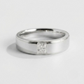A polished silver band ring featuring a single princess-cut diamond solitaire setting, photographed on a clean light gray background.