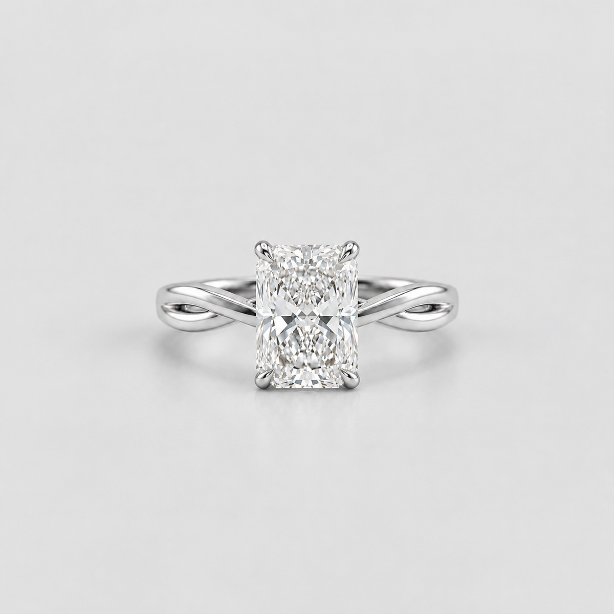 An radiant cut diamond engagement ring with a silver-colored split-shank band, centered on a light gray background.