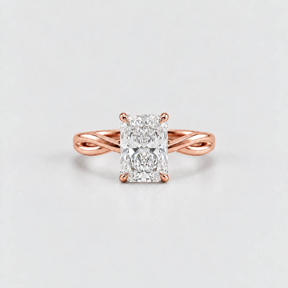 A rose gold engagement ring featuring a large rectangular radiant-cut diamond center stone, set on a split-shank band, photographed on a clean light gray background.