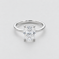 A classic solitaire engagement ring featuring a rectangular radiant-cut diamond set in a polished white gold or platinum band, photographed on a clean, light gray background.