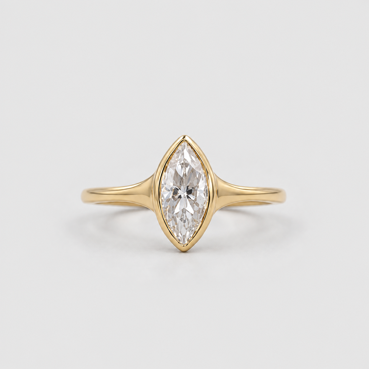 A yellow gold ring featuring a marquise-cut clear gemstone in a prong setting, centered on a light gray background.