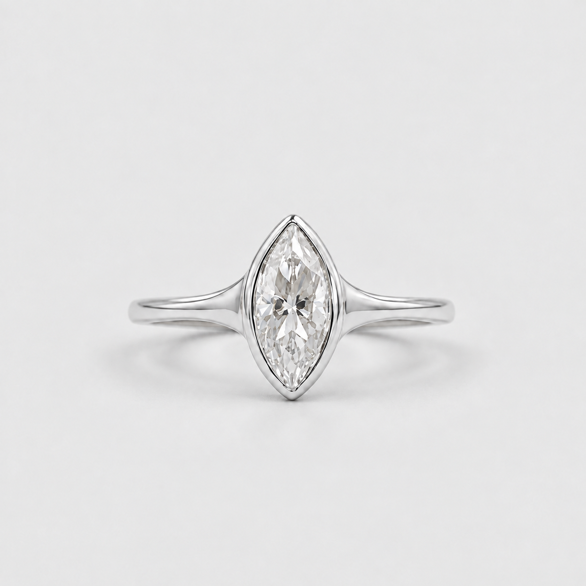 A silver marquise-cut diamond ring on a clean, light gray background.