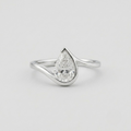 A silver ring featuring a pear-cut clear gemstone in a teardrop-shaped setting, shown on a clean light gray background.