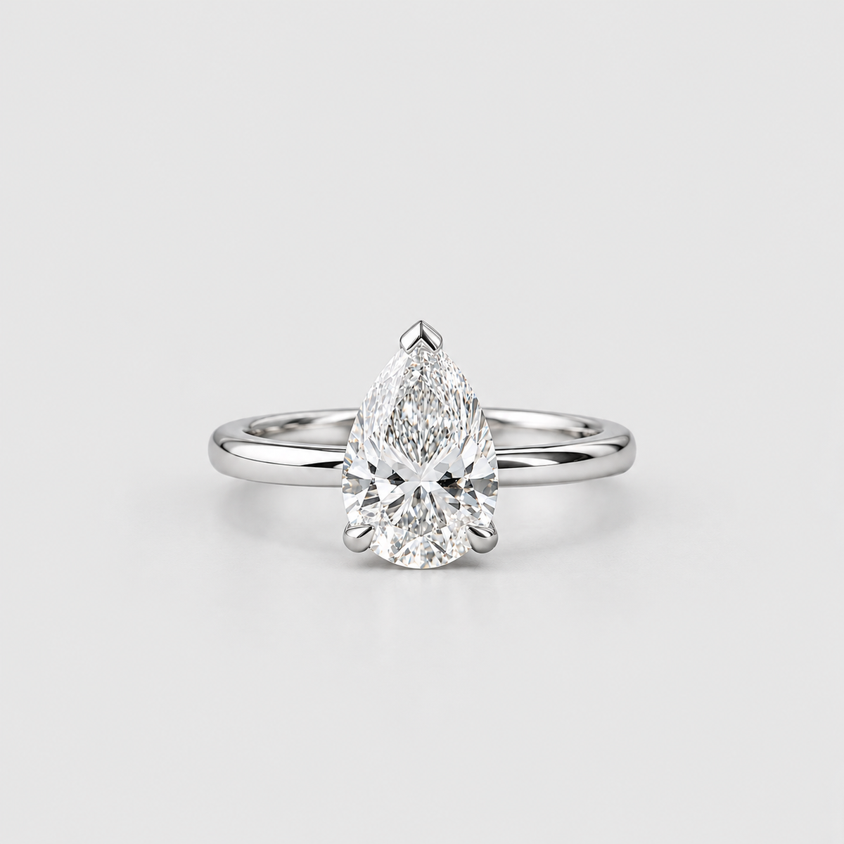 A pear-cut diamond solitaire ring in a polished silver-colored setting, centered on a light gray background.