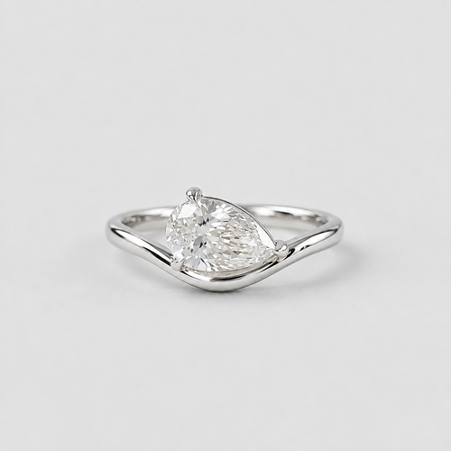 A silver ring featuring a pear-cut clear gemstone in a prong setting, mounted on a polished wavy band, shown against a light gray background.