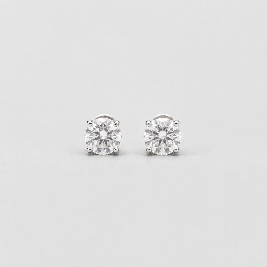 A pair of solitaire stud earrings with round brilliant-cut clear gemstones in a silver-toned four-prong setting, shown on a light gray background.