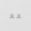 A pair of solitaire stud earrings with round brilliant-cut clear gemstones in a silver-toned four-prong setting, shown on a light gray background.