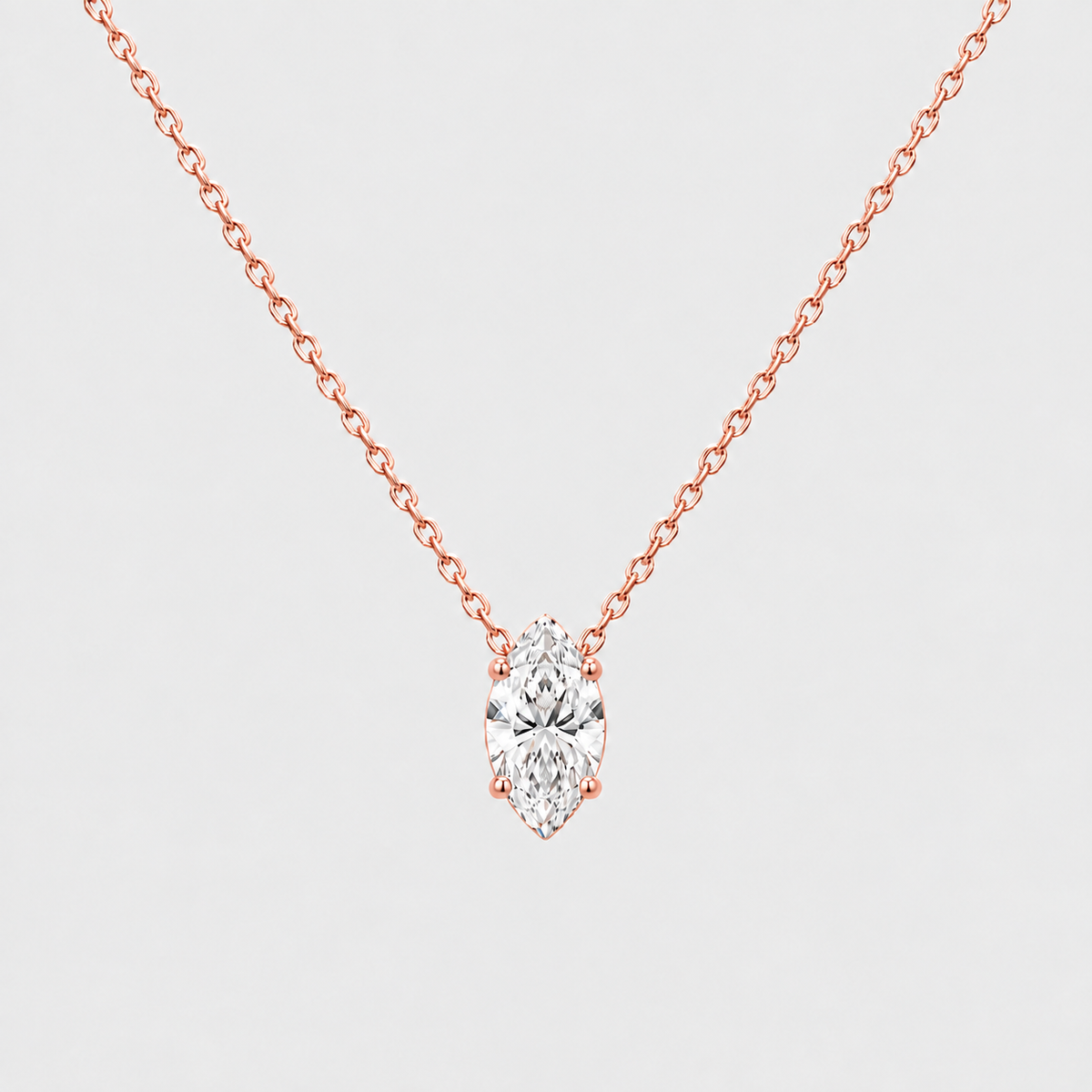 A rose gold necklace with a marquise-cut diamond pendant, shown against a light gray background.