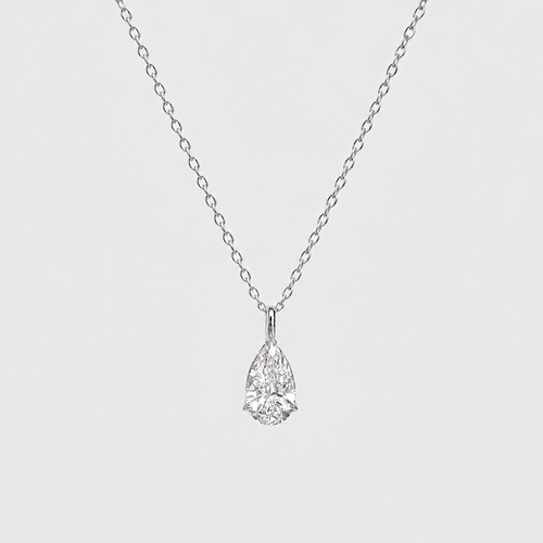 A pear-cut diamond pendant necklace on a delicate silver chain, presented against a solid light gray background.