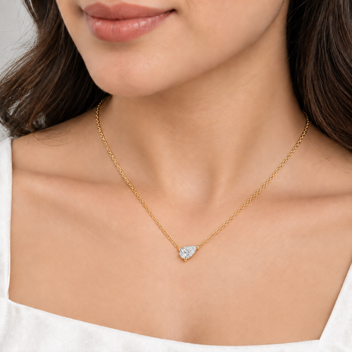A silver-toned chain necklace with a pear-cut clear gemstone pendant. The model shows the pendant. It looks very beautiful.