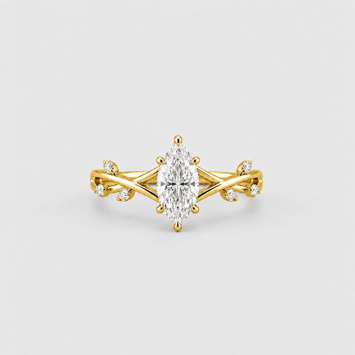 A yellow gold ring featuring a marquise-cut clear center stone and small accent stones on a twisted band, photographed on a clean light gray background.