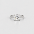 A princess-cut diamond engagement ring with a radiant cut center stone and a pavé-set diamond band, shown on a clean light gray background.