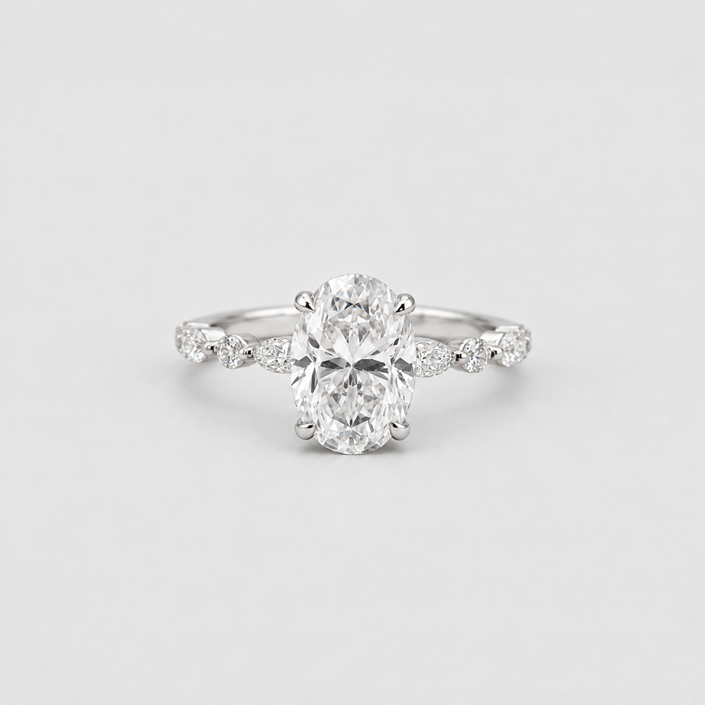 An oval-cut diamond engagement ring with a silver-toned band accented by small round diamonds, photographed on a clean light gray background.