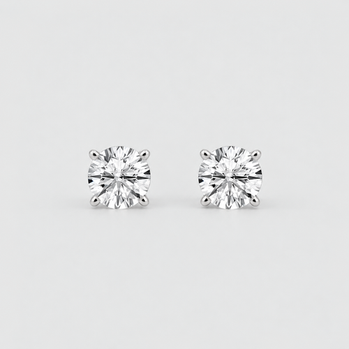 A pair of round-cut diamond stud earrings in a silver-toned setting, displayed on a clean light gray background.