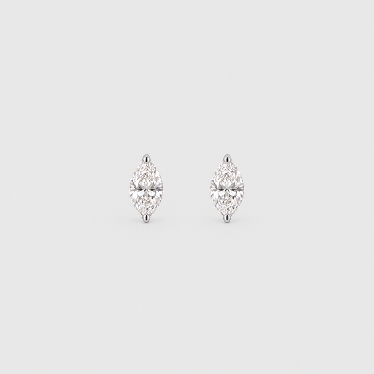 A pair of silver stud earrings with marquise-cut clear gemstones, set against a solid light gray background.