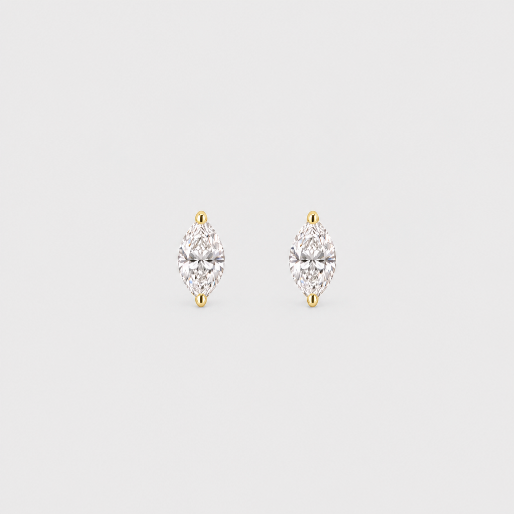 A pair of gold stud earrings with marquise-cut clear gemstones, set in a silver-toned prong setting on a light gray background.
