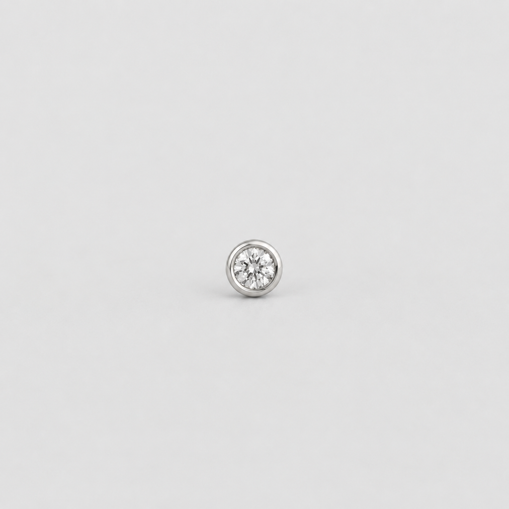 A single round bezel-set diamond stud earring in a silver-toned metal, centered on a light gray background.