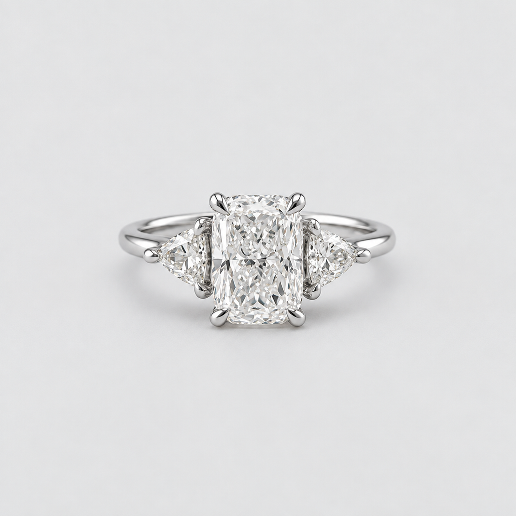 An elegant diamond ring featuring a central rectangular radiant-cut diamond flanked by two small triangular diamonds on a polished silver-colored band, set against a clean light gray background.