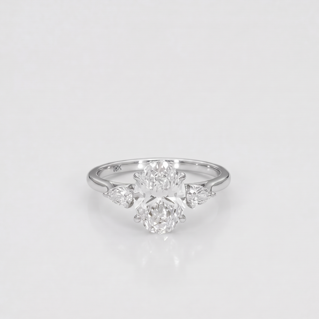 A silver-toned diamond ring featuring a central round brilliant-cut diamond surrounded by three marquise-cut diamonds on a smooth band, set against a clean white background.