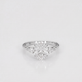 A silver-toned diamond ring featuring a central round brilliant-cut diamond surrounded by three marquise-cut diamonds on a smooth band, set against a clean white background.