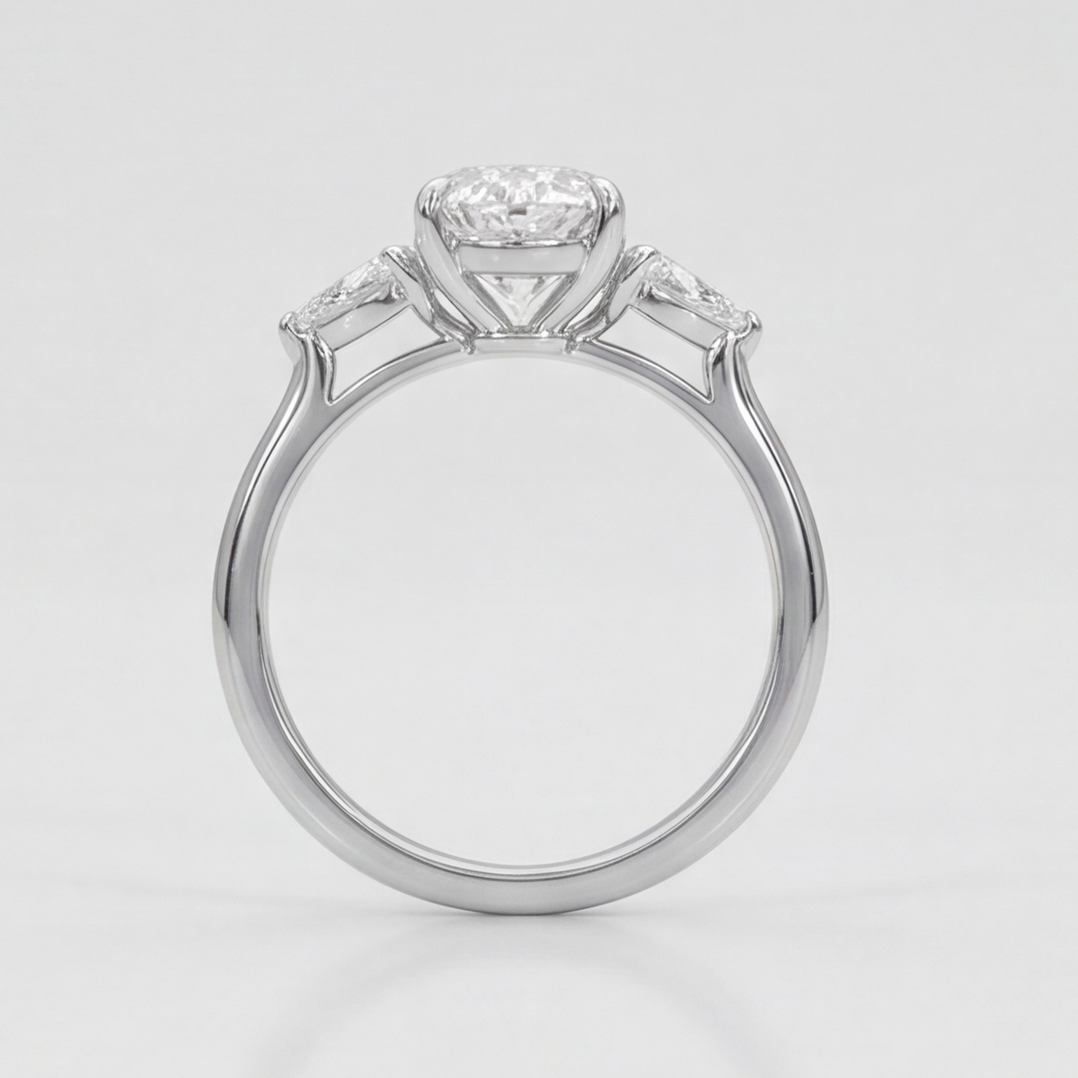 A silver-toned solitaire engagement ring with a round-cut center stone and smaller side stones, shown on a clean light gray background.